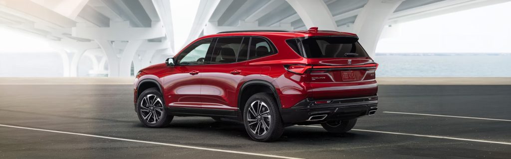 Red Buick Enclave SUV parked on a modern roadway under a bridge.