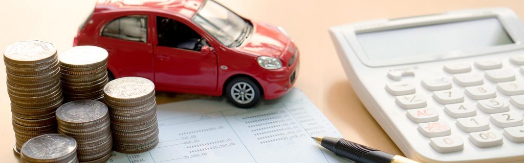 Car finance calculator with coins and vehicle payment documents.
