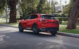 Red 2026 Buick Envision driving on a tree-lined street