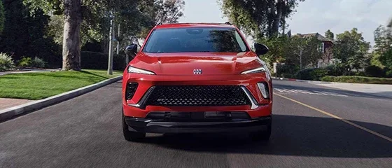 2026 Buick Envision in red driving down a tree-lined residential street, head-on view