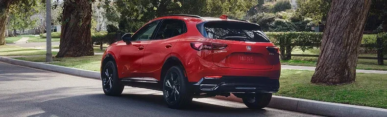 Rear three-quarter view of a red Buick Envision parked on a tree-lined residential street