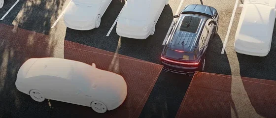 Overhead view of a 2026 Buick Enclave backing out of a parking space with rear sensor zones highlighted around it