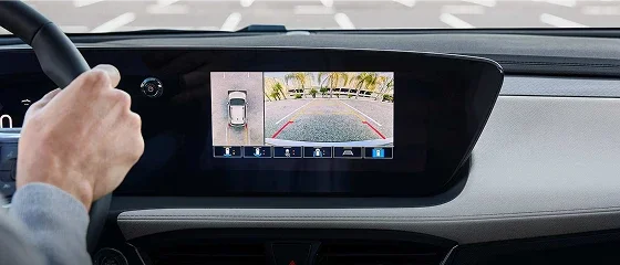 Driver's hand on the wheel of a 2026 Buick Encore GX Preferred with the dash touchscreen showing the parking camera view