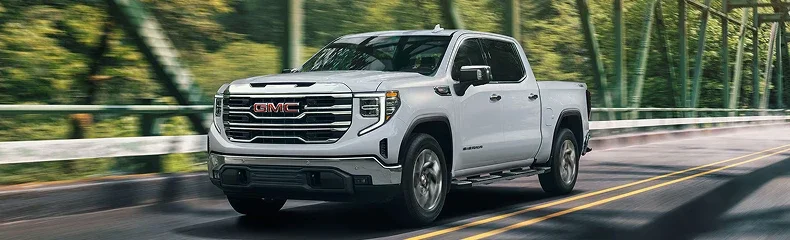 White GMC Sierra SLT pickup crossing a green truss bridge