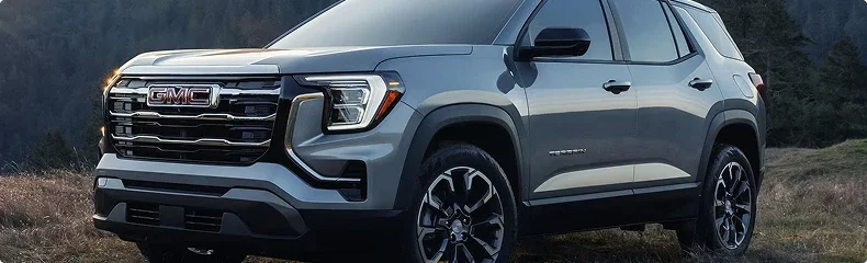 Grey GMC Terrain SUV parked on a hillside with wooded slopes behind it