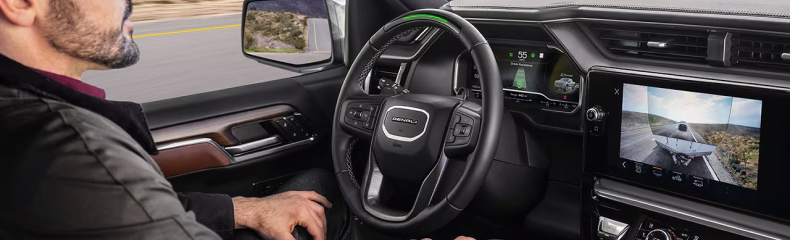 Driver using hands-free driver assistance in a GMC Denali cabin with the trailer camera on screen