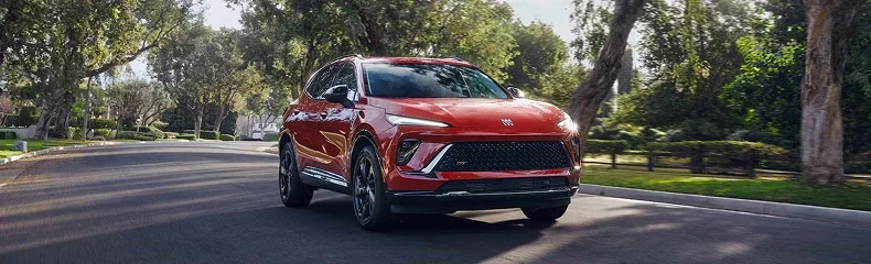 Red Buick crossover driving down a tree-lined suburban street