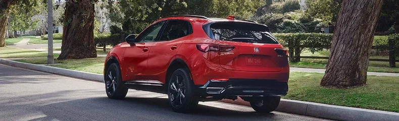 Rear three-quarter view of a red Buick Envision Sport Touring on a tree-lined street