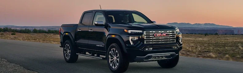 Black GMC Canyon Denali parked on a desert road at sunset